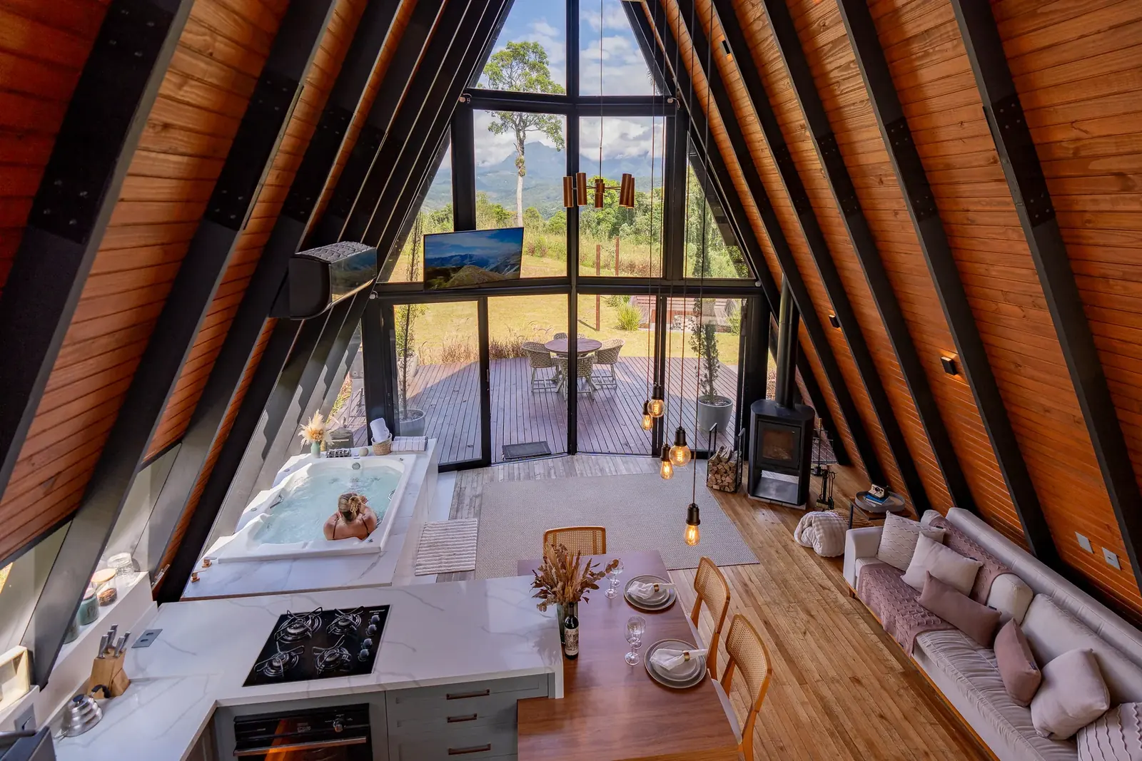 Sala integrada com cozinha completa, lareira, sofá-cama, hidromassagem e vista para as montanhas